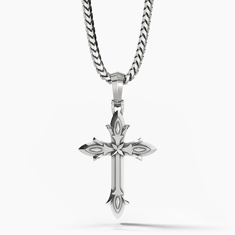 a sterling silver cross necklace with layered decorative sculpting hangs from a chain