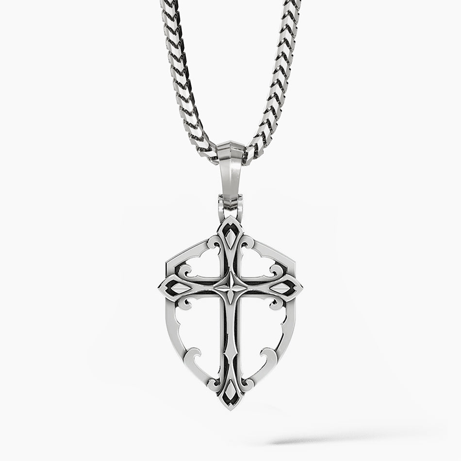 a sterling silver cross necklace in the shape of a shield hangs from a chain