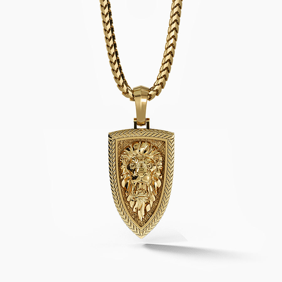 a gold lion head pendant is sculpted into the shape of a shield with a pattern around the border