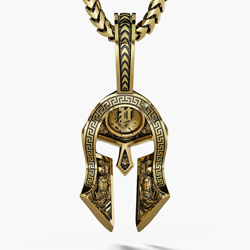 the back of a gold Spartan pendant shows two Spartan warriors carved into the helmet