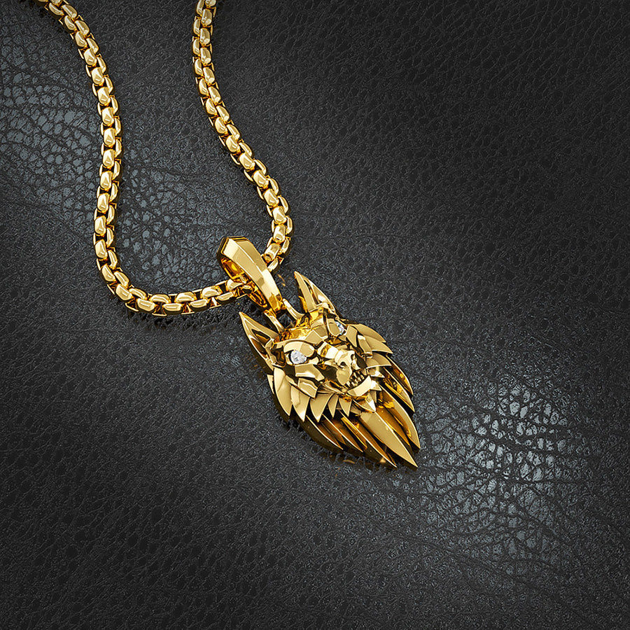 a gold wolf necklace lies on slate with a 14 karat crown ring