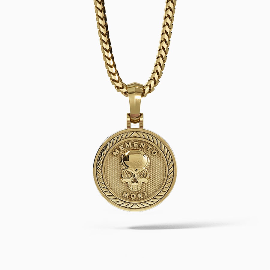 a gold skull pendant in the shape of a medallion with the words memento mori inscribed