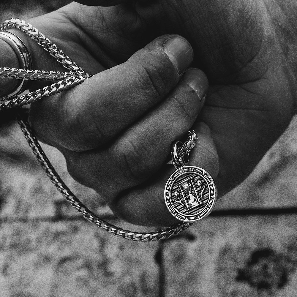 the silver hourglass and tulips shine on the back of a silver memento mori pendant