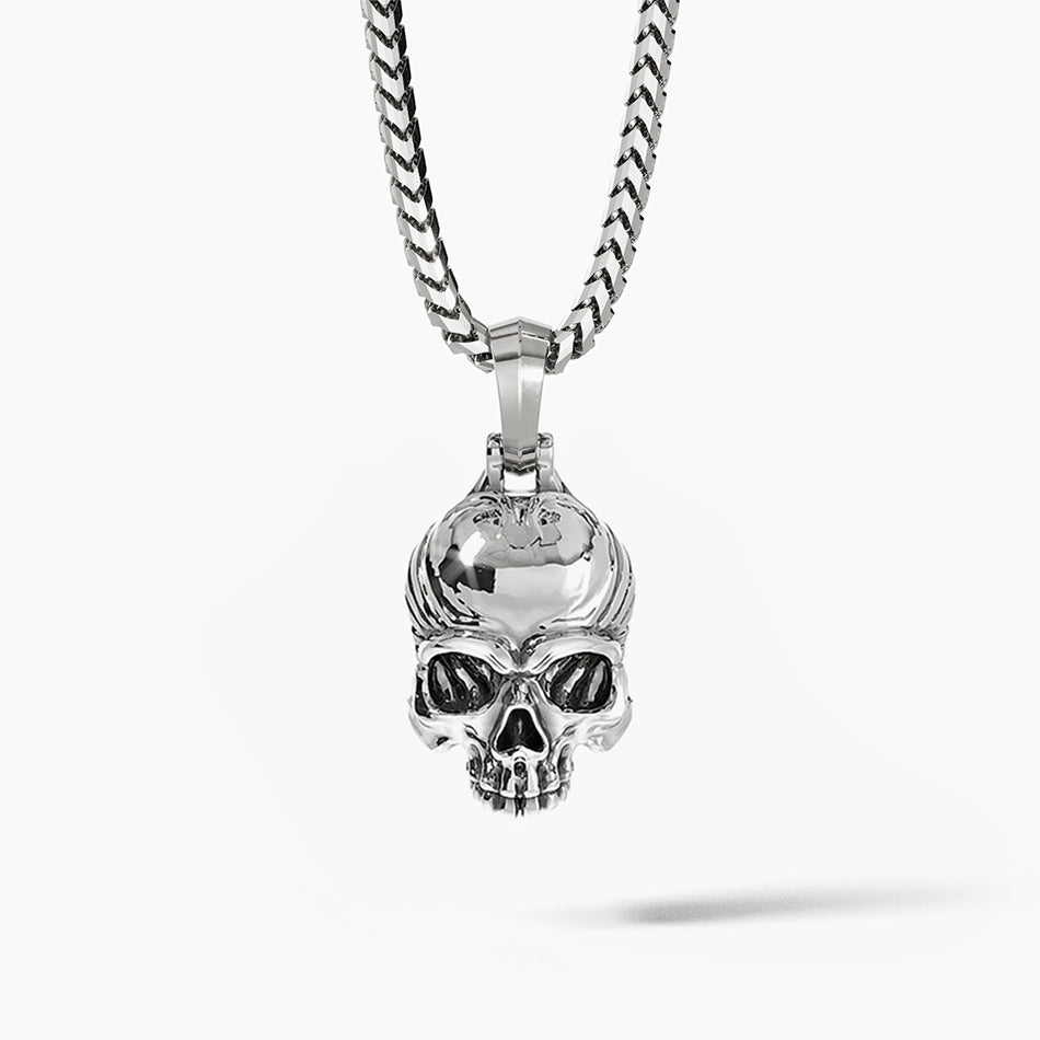 a silver skull pendant hangs on a silver chain