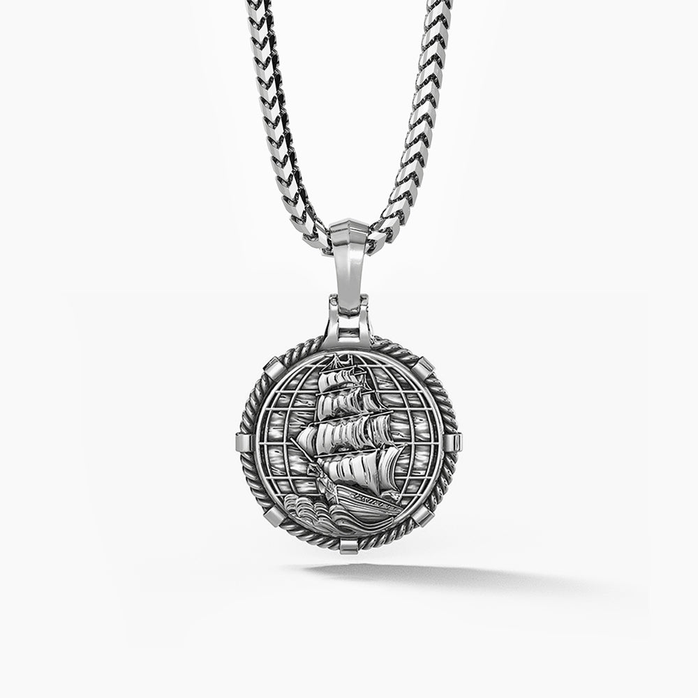 The back of a silver pendant features a nautical ship and globe