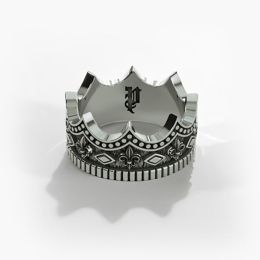 a mens silver ring sculpted into a crown lies on a black surface