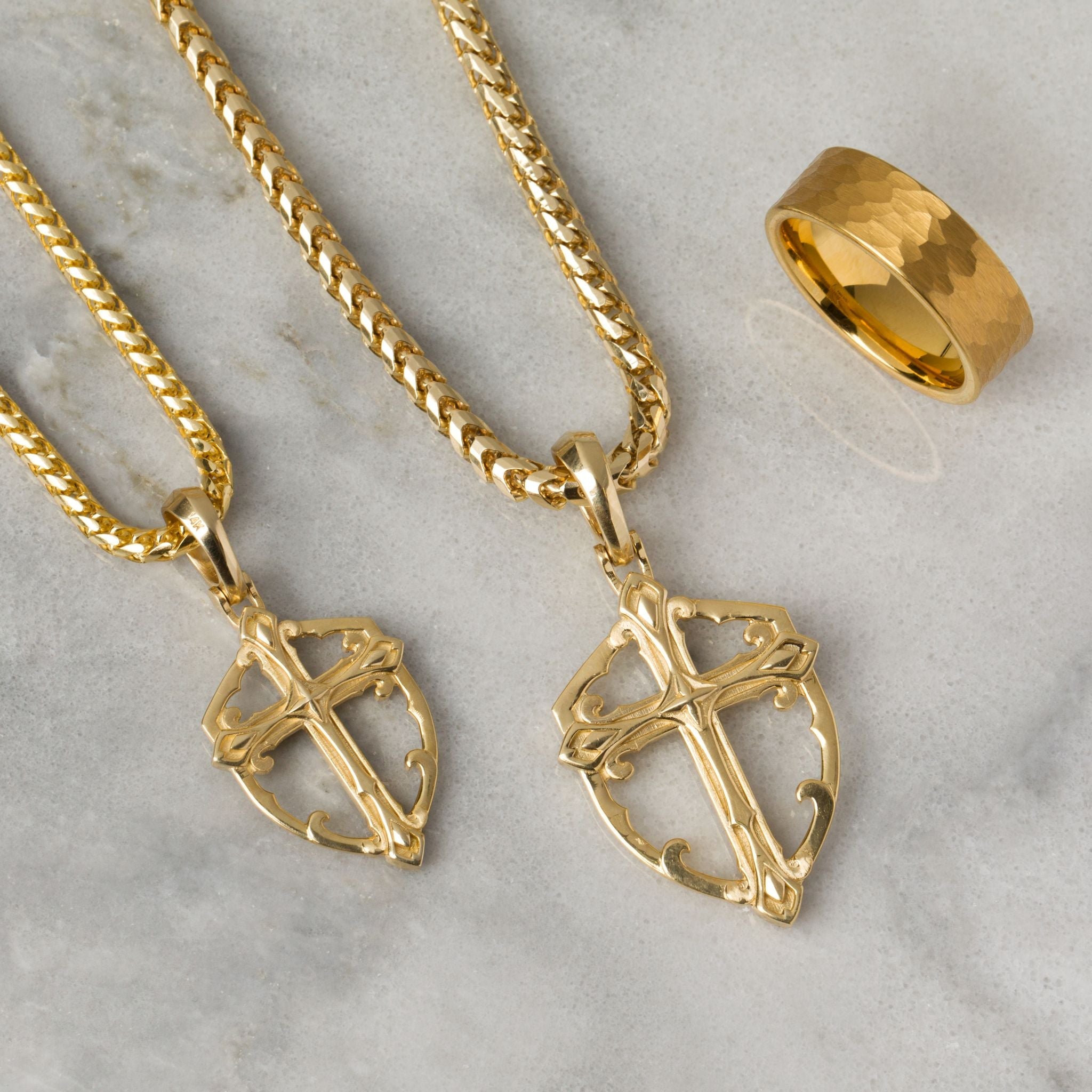 two polished yellow gold necklaces crosses shine as they lie on a white marble surface