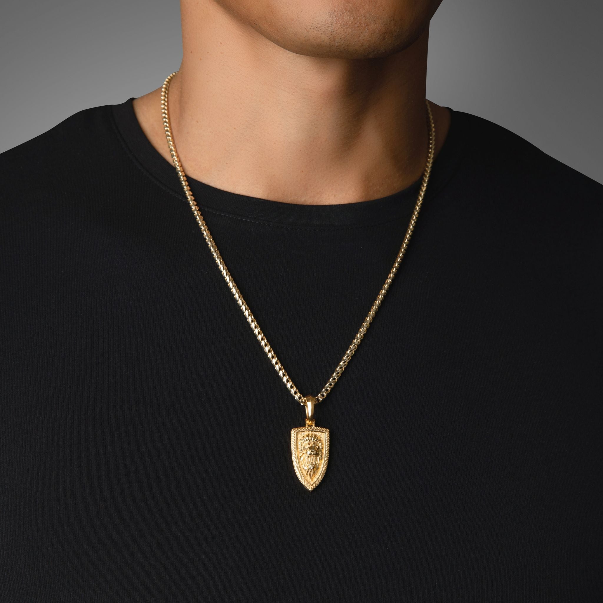 a man in a black shirt wears a polished gold lion pendant