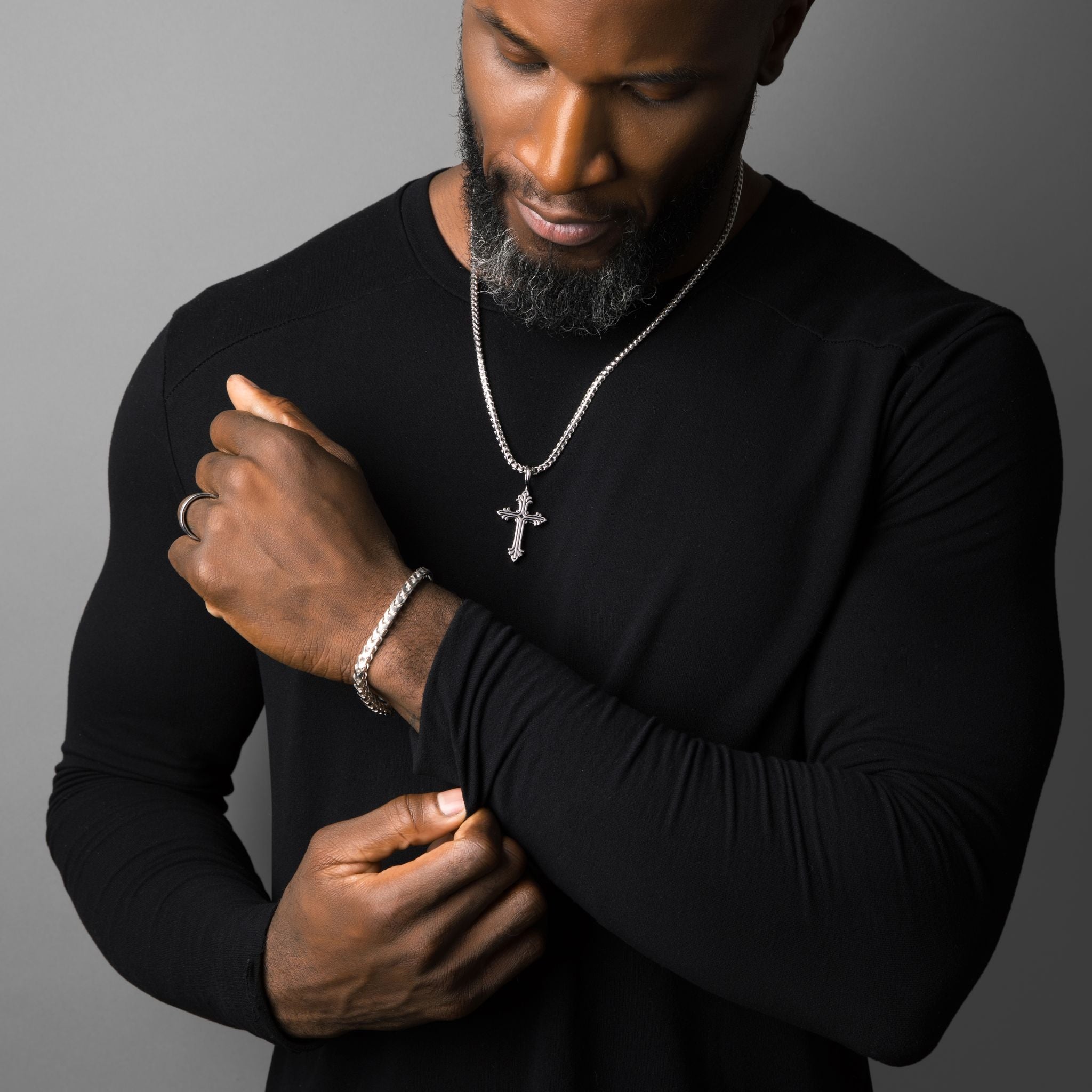 a sterling silver cross necklace is worn by a muscular man with a black shirt