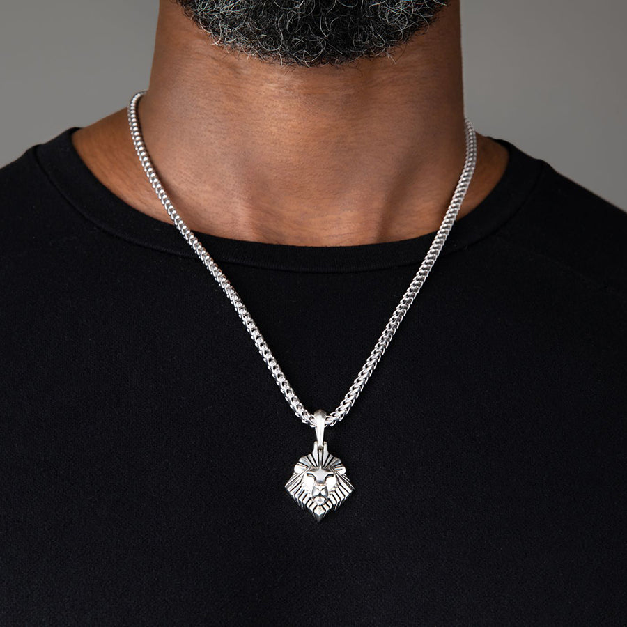 a large silver lion head pendant hangs from a man's franco chain