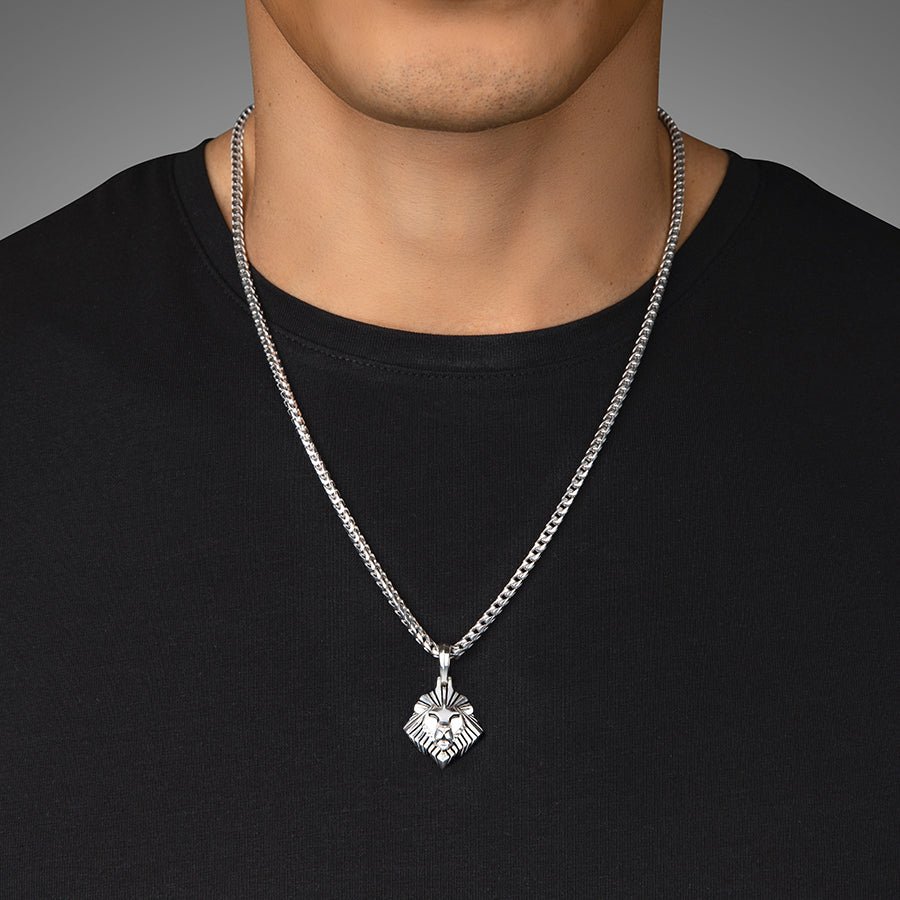 a man in a black shirt wears a polished silver lion pendant