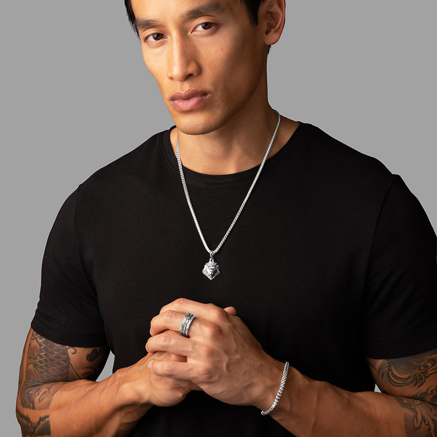 a man in a black shirt wears a silver lion pendant