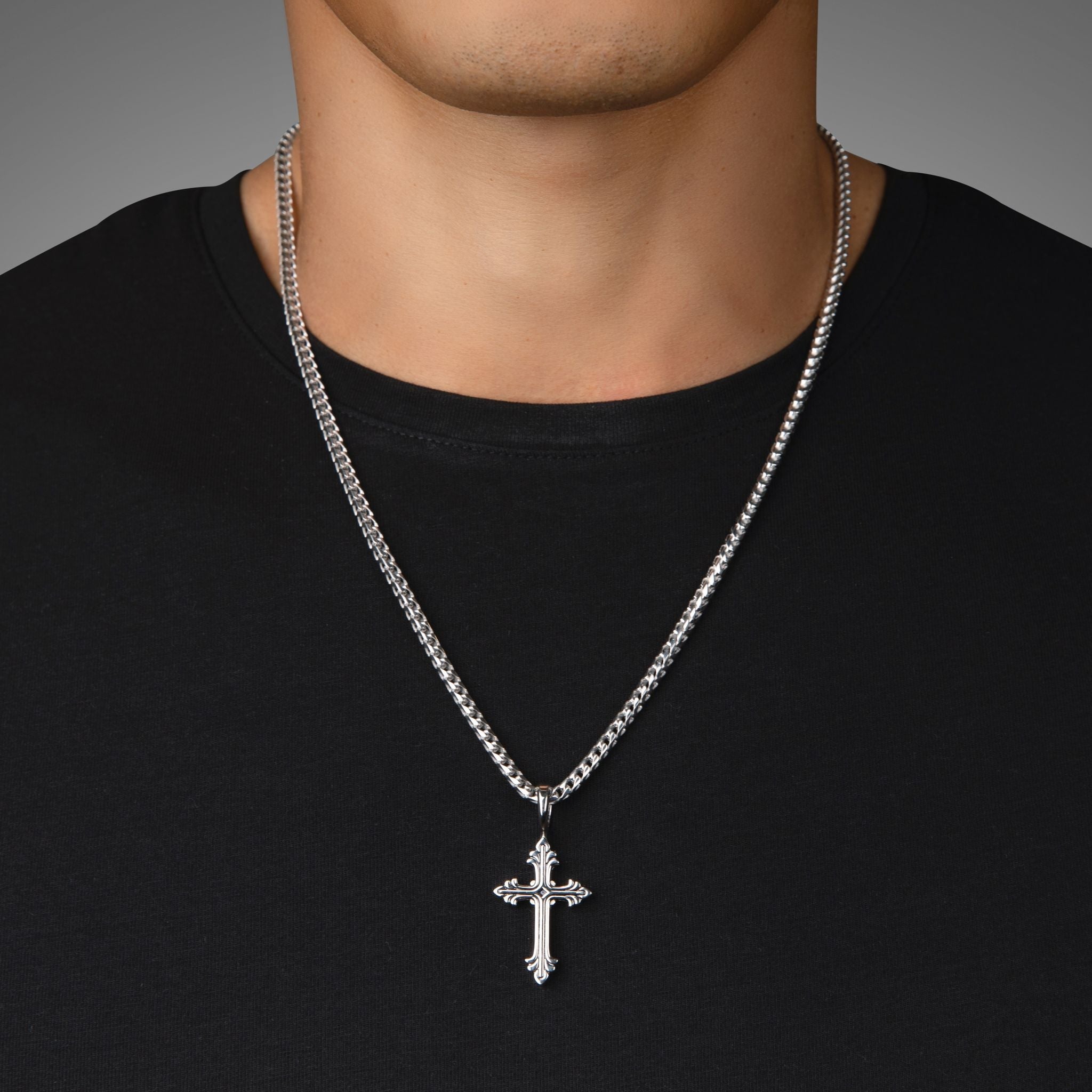 a man in a black shirt wears a sterling silver cross pendant