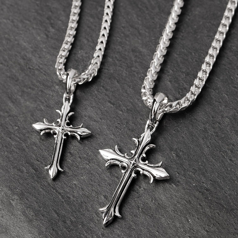 two silver cross chains lie on a slate surface