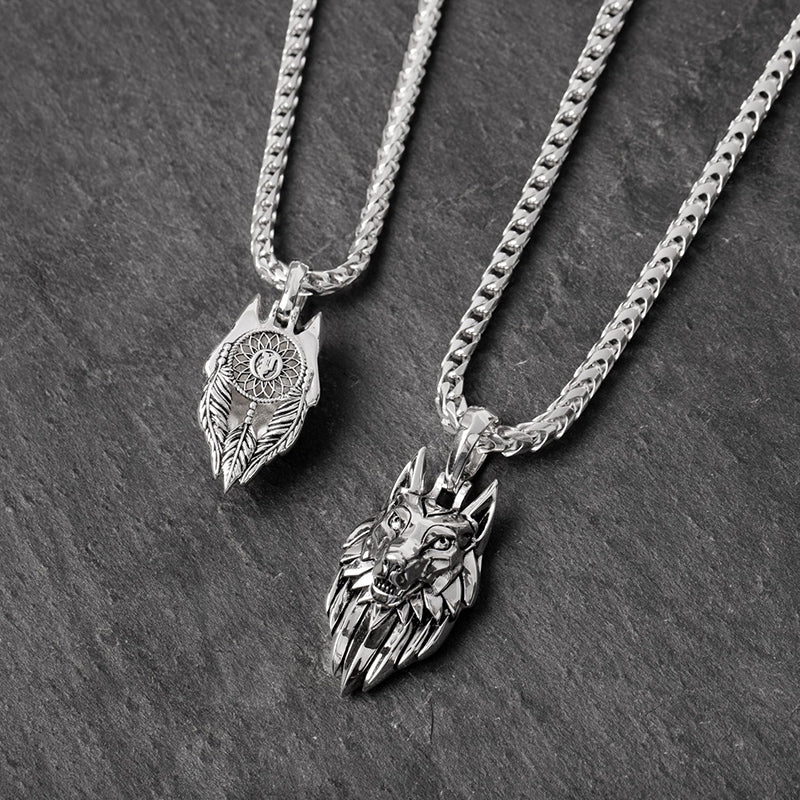 two silver wolf pendants lie on slate, one showing the dreamcatcher on the back